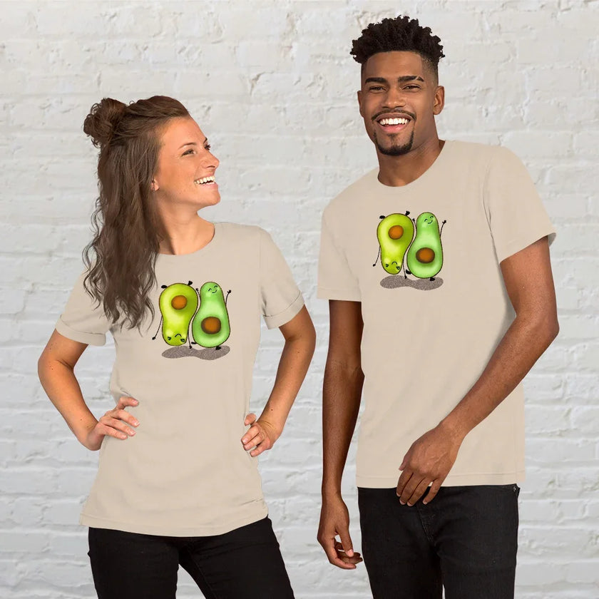 Two people wearing matching cream white Avocado Harmony  graphic tees, featuring two cute avocados doing yoga poses, styled as a fun, wholesome lifestyle outfit.