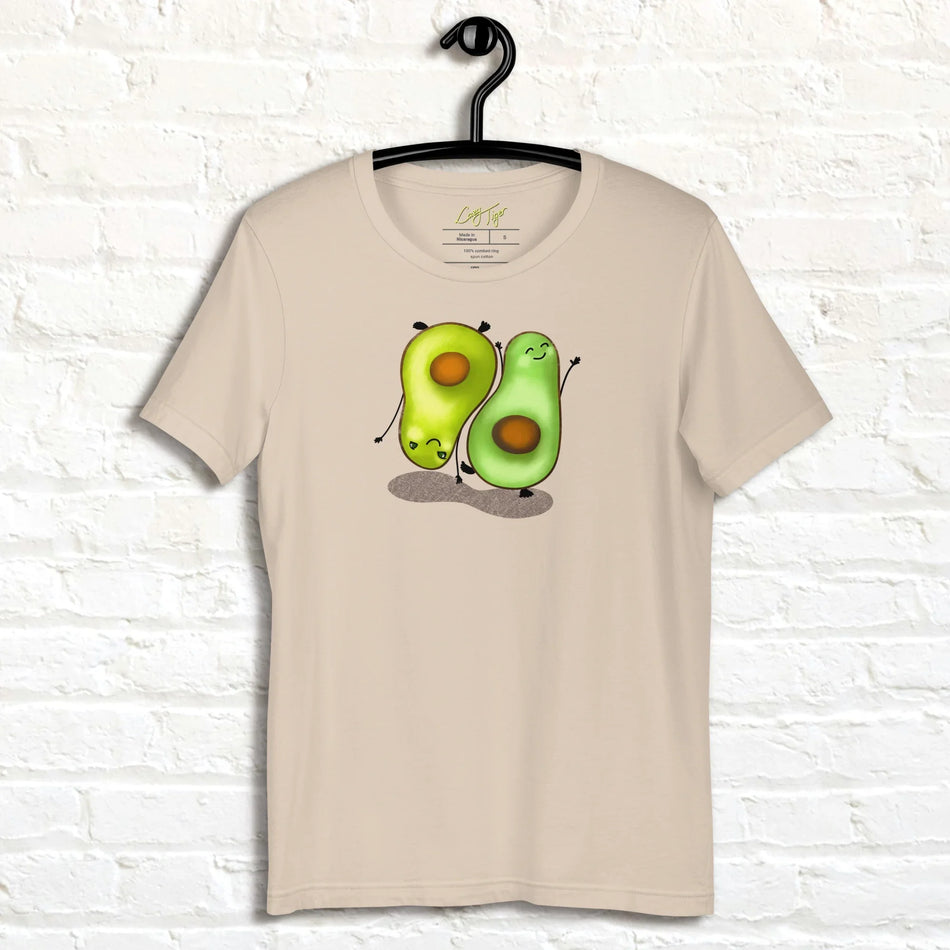 Cream white Avocado Yoga Tee displayed on a hanger, featuring two cute avocados performing yoga poses with expressive faces and playful movement.