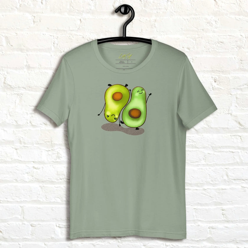 Sage green Avocado Yoga Tee hanging on a wall, showing two cartoon avocados doing yoga exercises with charming expressions and soft, aesthetic colors.