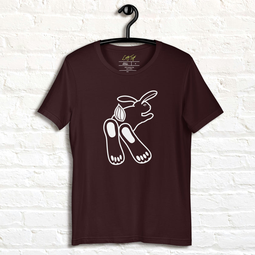 Chill Bunny Line Art Tee hanging against a white brick wall, showing the relaxed rabbit outline on a dark brown shirt.