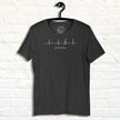Heather charcoal Lost in Music Line Art Tee hanging against a white wall, showing the ECG‑style heartbeat flowing into a treble clef with the ‘Lost in music…’ text.