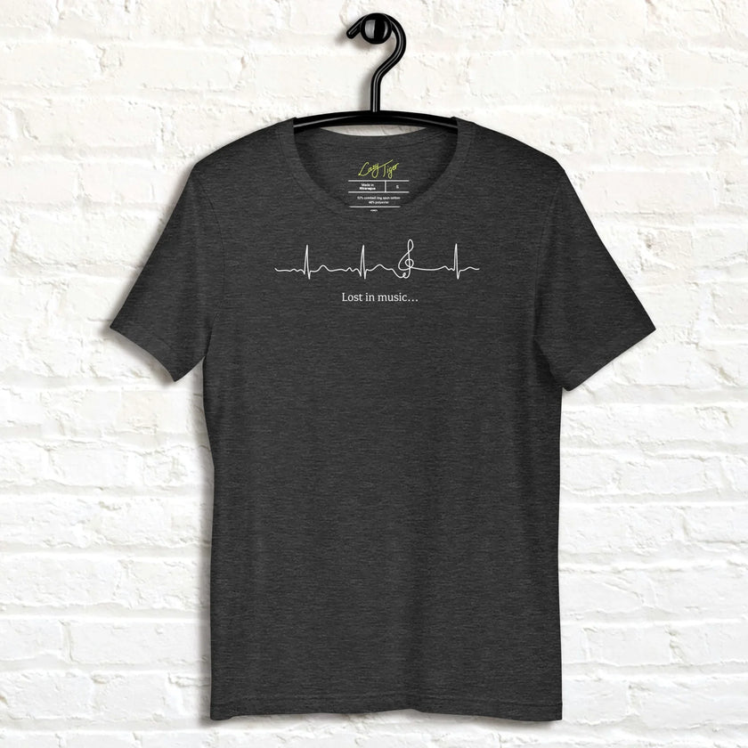 Heather charcoal Lost in Music Line Art Tee hanging against a white wall, showing the ECG‑style heartbeat flowing into a treble clef with the ‘Lost in music…’ text.