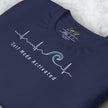 Close-up detail of a folded navy Surf Mode Activated Tee, highlighting the clean white surf‑wave line art and smooth print texture.