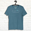 Heather dark teal Surf Mode Activated Tee hanging on a wall, showing the heartbeat‑to‑wave graphic and ‘Surf Mode Activated’ text in white.
