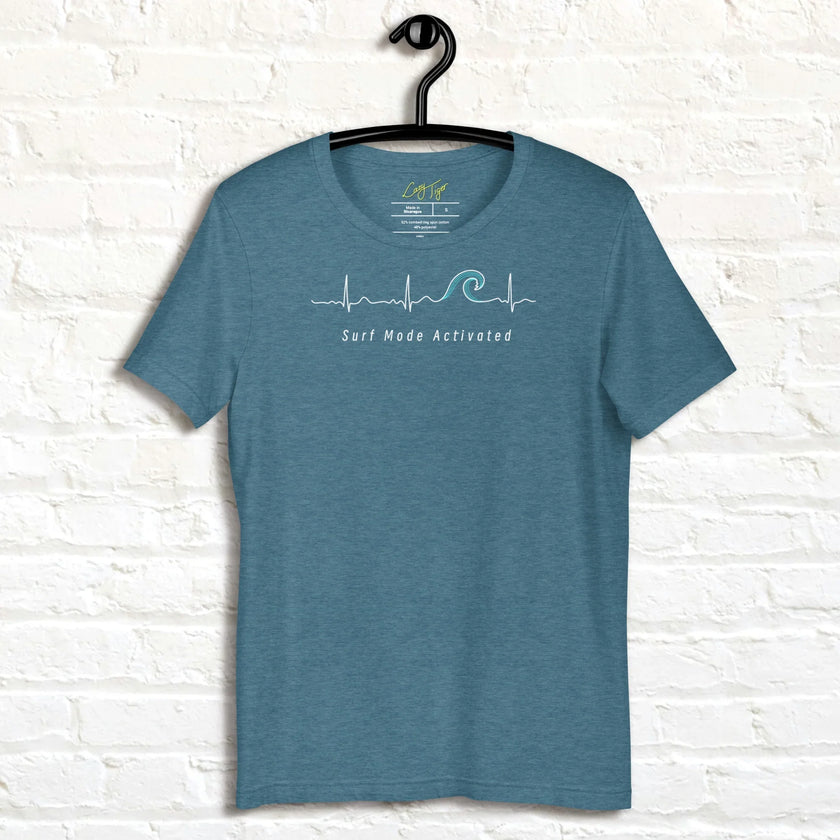 Heather dark teal Surf Mode Activated Tee hanging on a wall, showing the heartbeat‑to‑wave graphic and ‘Surf Mode Activated’ text in white.