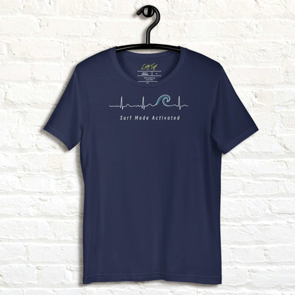 Navy Surf Mode Activated Tee hanging against a white wall, showing the minimalist heartbeat line transforming into a surf wave with the ‘Surf Mode Activated’ script.