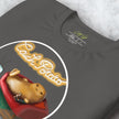 Close-up detail of a folded graphite grey Lazy Potato Tee, highlighting the couch‑potato illustration, remote, TV, and neon script.