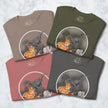 Set of four folded Pizza Raptor T‑shirts in olive, graphite, rosewood, and taupe, featuring cartoon dinosaur stealing pizza, funny unisex graphic tees in multiple colors.