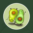 Closeup of two cute avocados in opposite yoga‑style poses, one standing and one upside down on its hands, printed on a forest green tee