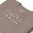 Detail shot of the taupe Heartbeat Surf Tee showing the printed neck label and the ECG‑style heartbeat line flowing into a surf wave, with crisp white print on smooth cotton fabric