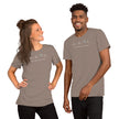 Model wearing the taupe Heartbeat Surf Tee with the ECG‑style heartbeat‑wave surf design and ‘Surf Mode Activated’ text, creating a warm neutral surf‑lifestyle aesthetic