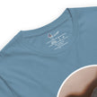 Detail shot of a dinosaur print and brand label on a denim blue tee