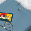 Close-up detail of a folded denim blue Retro Vibes Cassette Tee, highlighting the colorful cassette illustration and heart‑shaped tape.