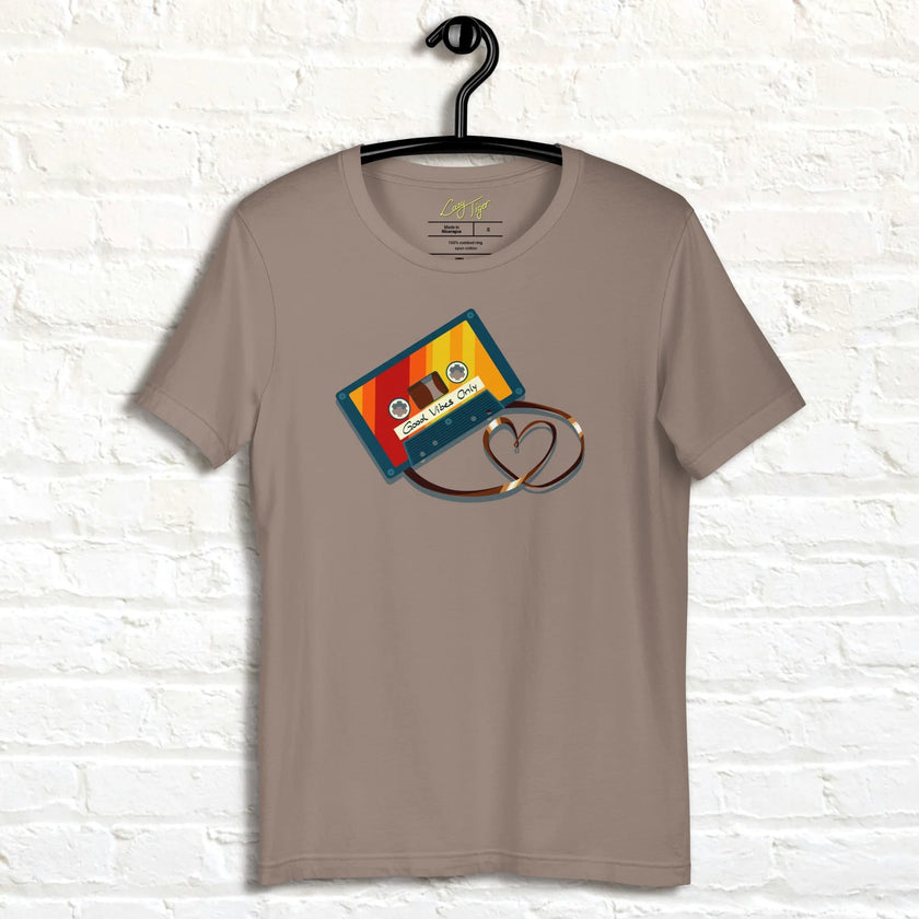 Taupe Retro Vibes Cassette Tee hanging against a white wall, showing the colorful retro cassette illustration with heart‑shaped tape.