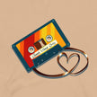 Closeup of a retro cassette in bold vintage colors with its tape forming a heart shape, printed on a beige tee