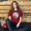Lifestyle mockup of a burgundy tee with a smiling red vintage camper van on a surf board, surfing a giant barrel wave on a sunny day